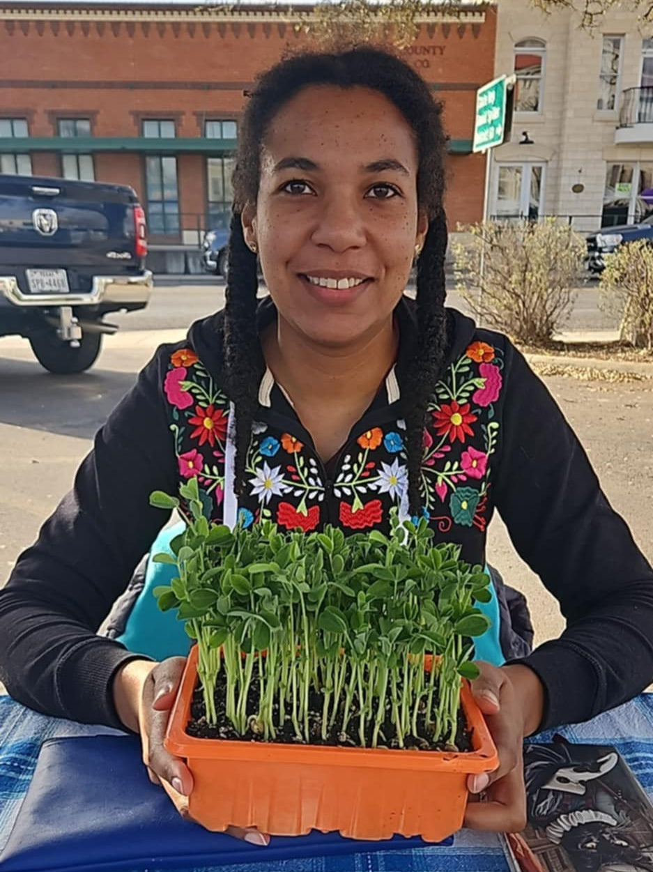 Black woman holding a container of growing pea shoots